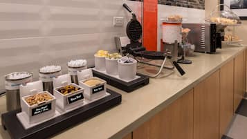 Ein Frühstücksbuffet mit verschiedenen Speisen und einem Waffeleisen.