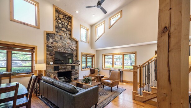 A spacious living room with a stone fireplace, wooden flooring, and large windows. - Engen Hus Bed and Breakfast (Salt Lake City)