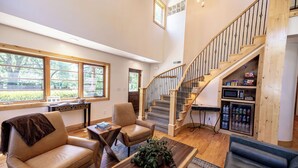 A spacious living room with a wooden staircase, leather sofas, a coffee table, and large windows. - Engen Hus Bed and Breakfast (Salt Lake City)