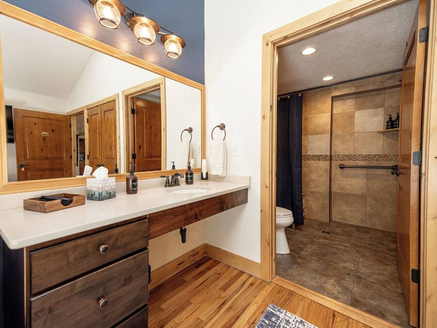 A bathroom with a wooden vanity, a large mirror, and a shower area.