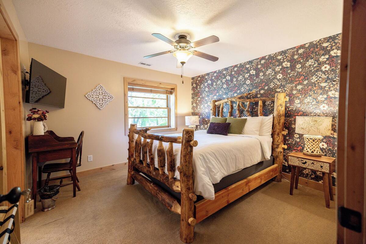 A bedroom with a wooden bed frame, a desk, and a chair.