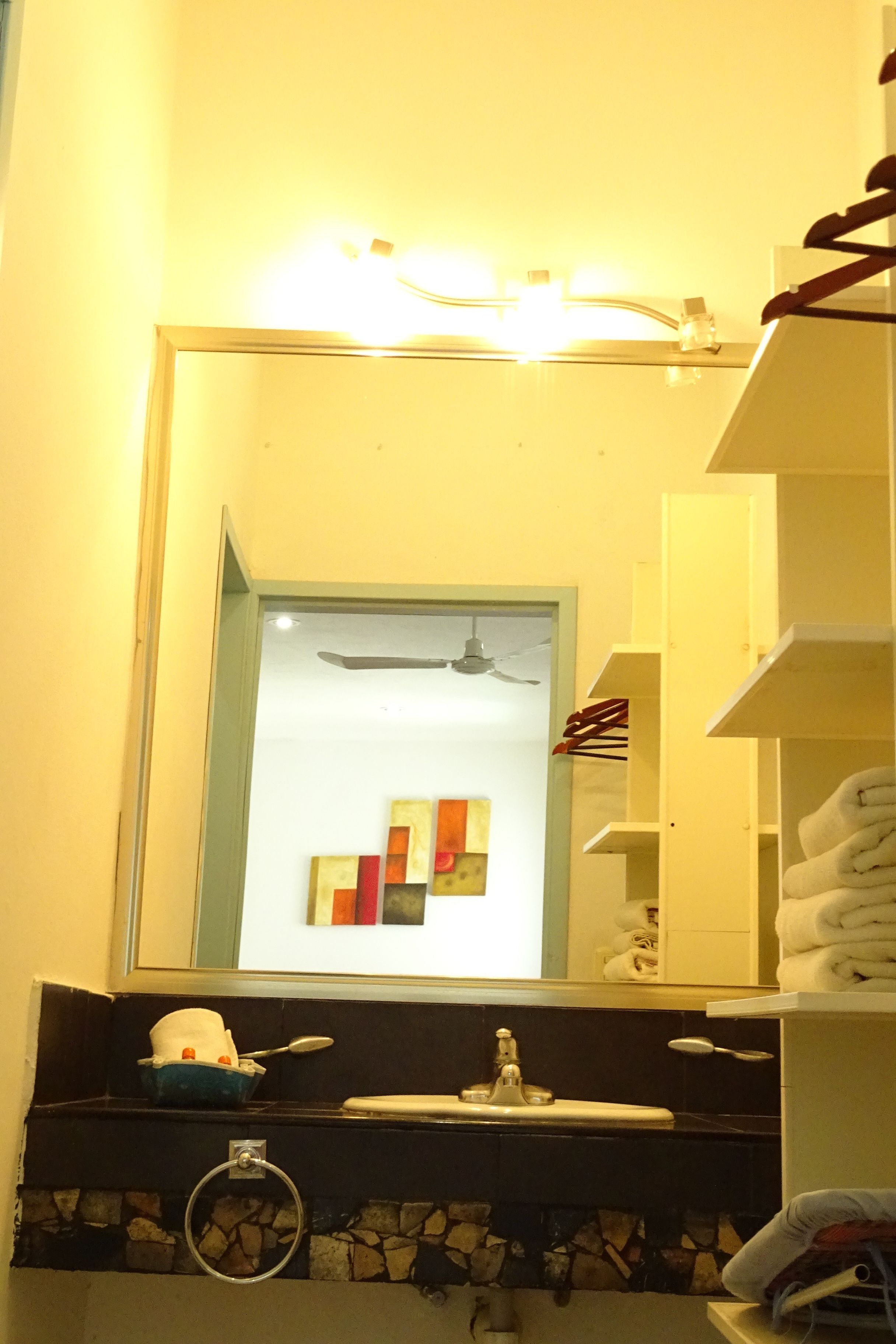 A bathroom with a mirror, sink, towel rack, and a towel dispenser.