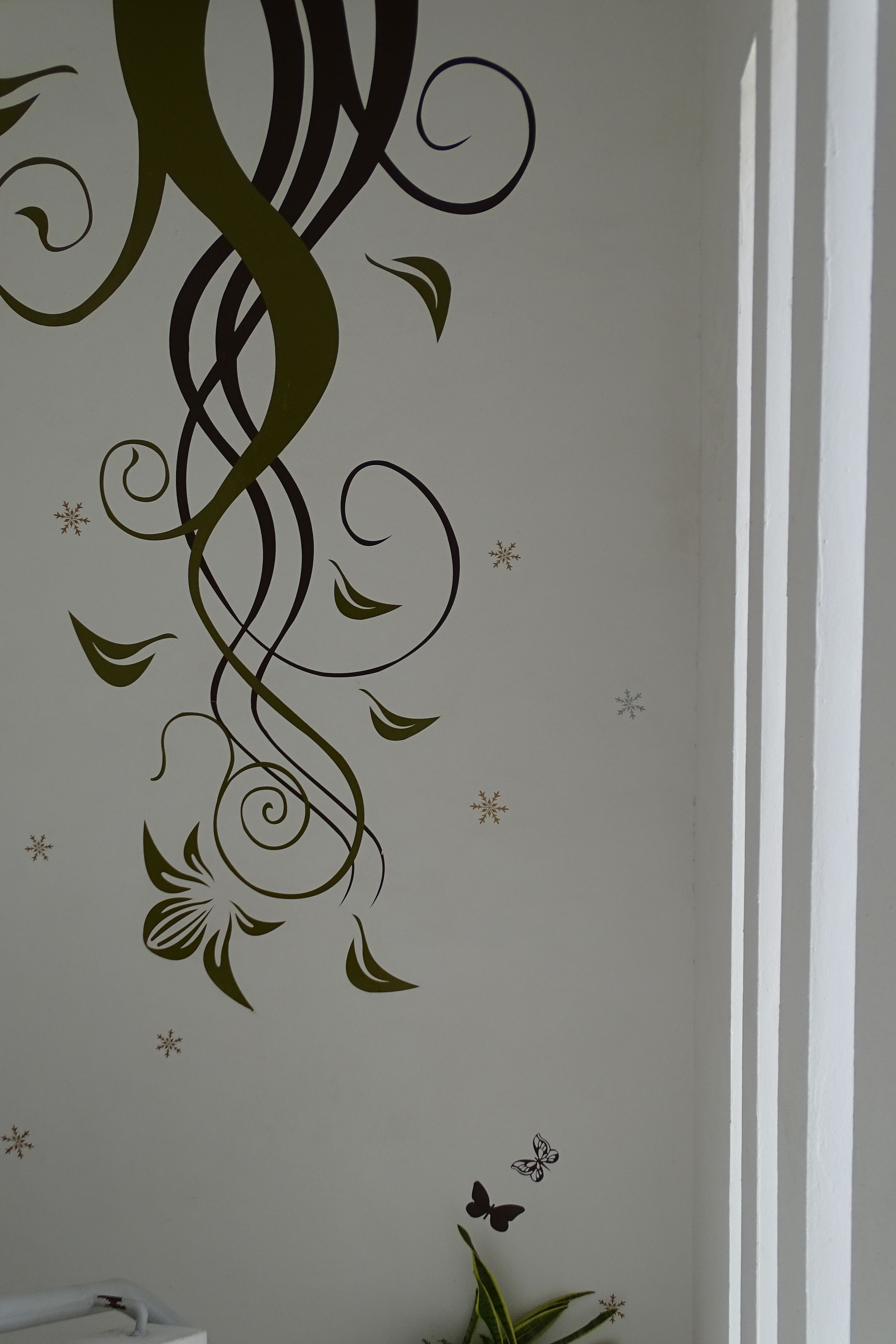 A wall with a decorative design featuring a large 'M' and floral elements.