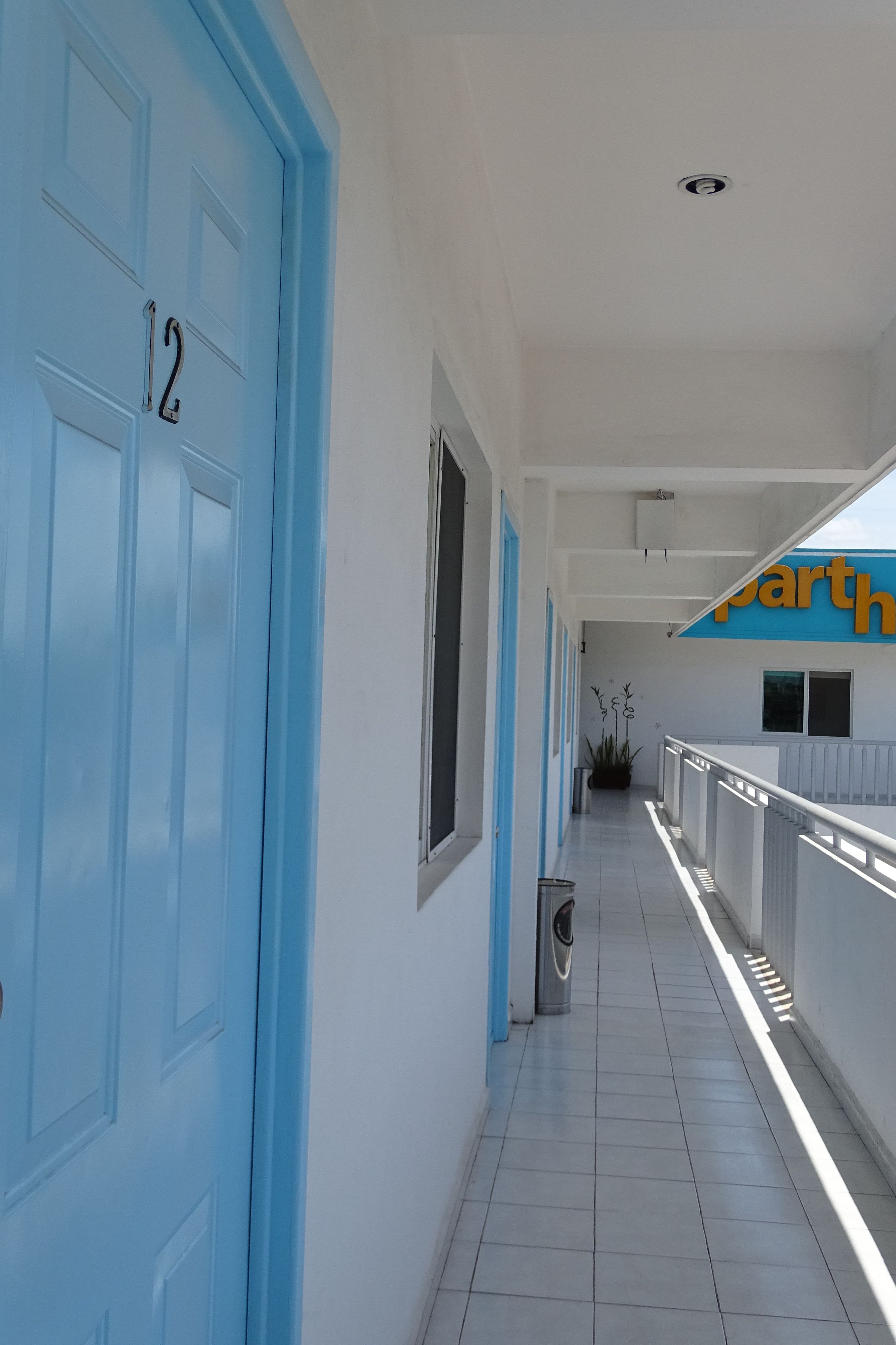 A corridor with blue doors, a trash bin, and a sign for 'parth'.