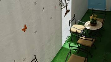 A room with a green carpet, white walls with butterfly decals, a blue door, and a row of tables with chairs.