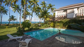 Un espace piscine avec des chaises longues, un jacuzzi et une vue sur l’océan.