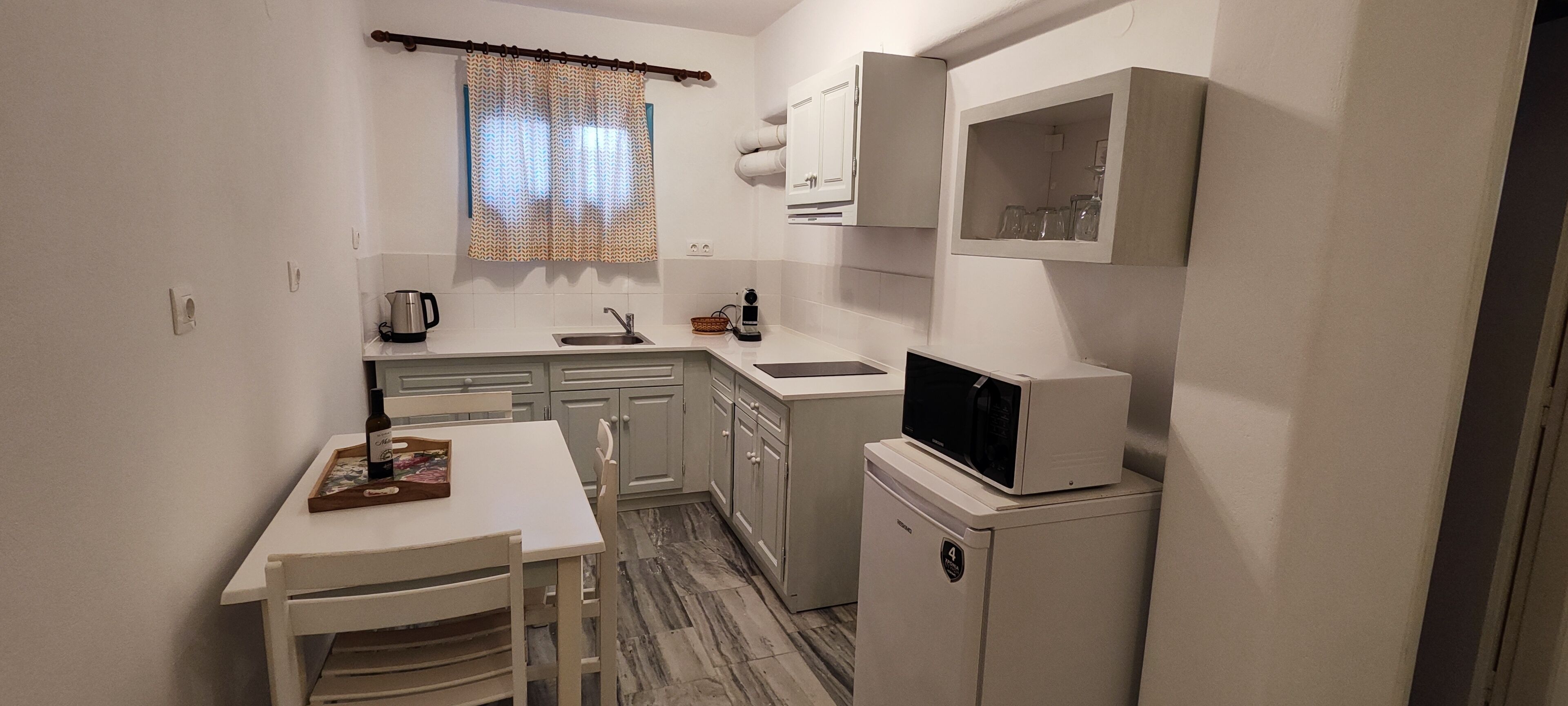 A compact kitchen with a white table, a microwave, and a refrigerator.