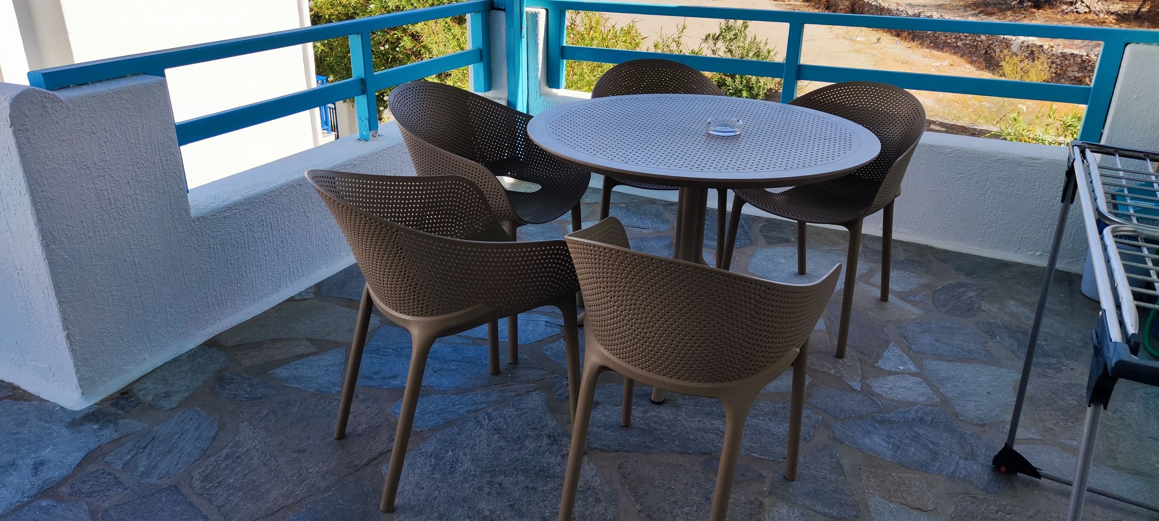 An outdoor patio with a round table and four wicker chairs.