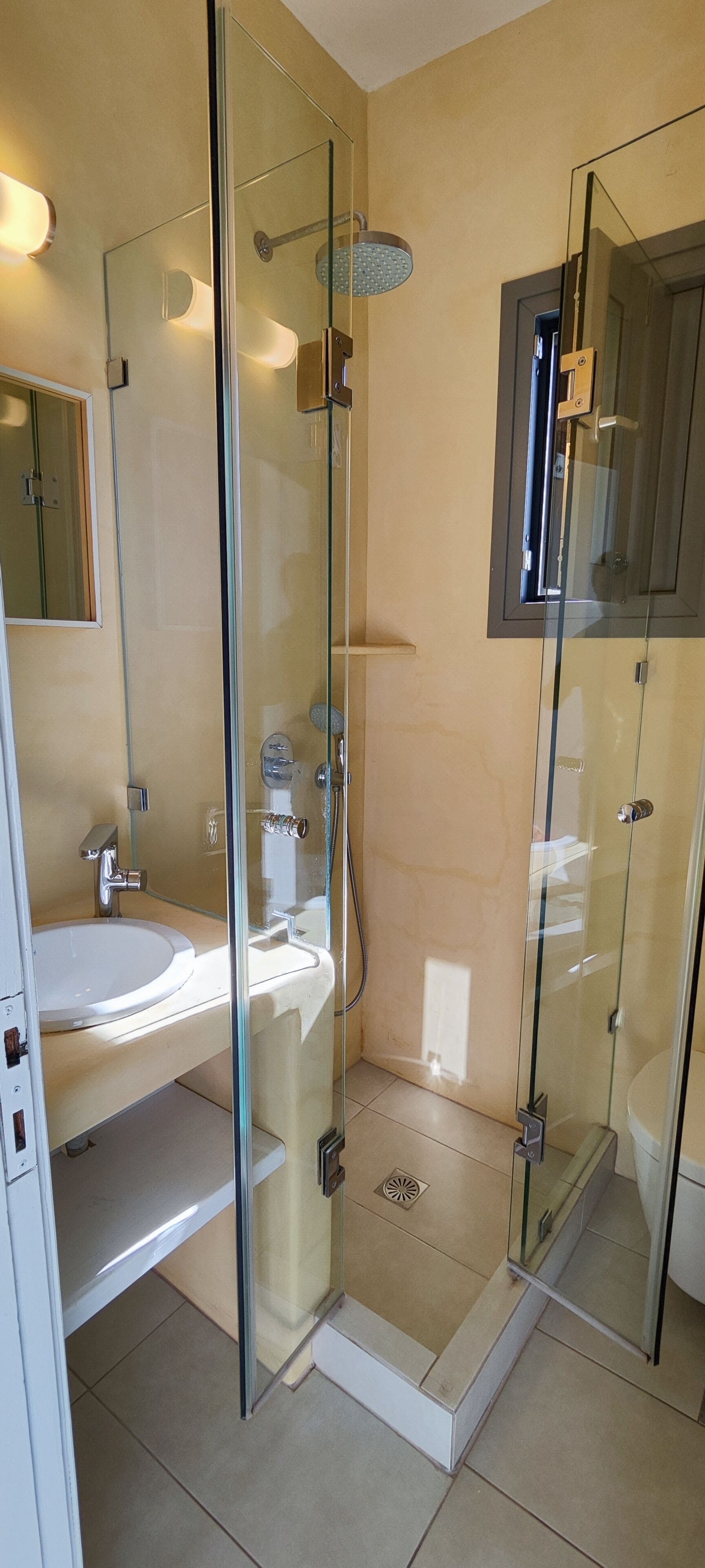 A modern bathroom with a glass-enclosed shower, a sink, and a toilet.