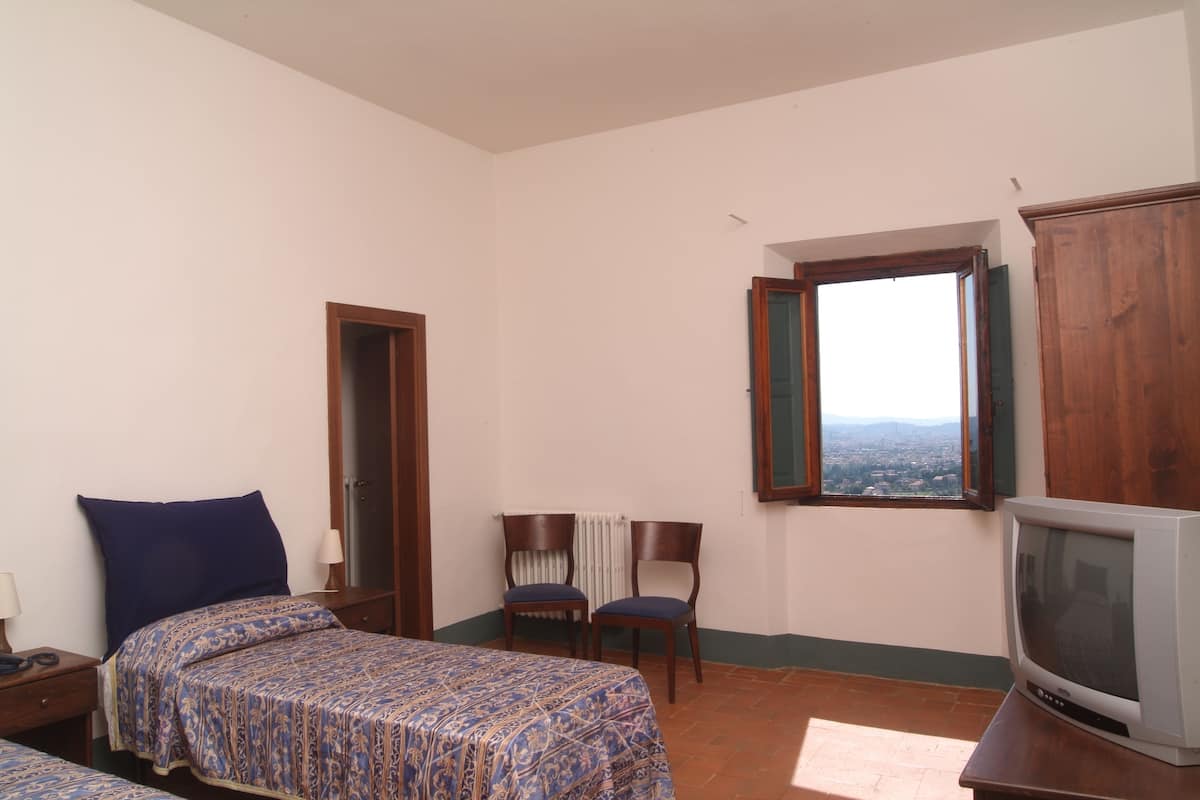 Un dormitorio con dos camas, una televisión, un ventanal con vistas y una silla.