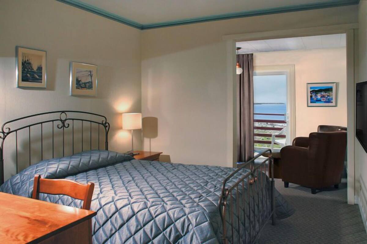 Ein Hotelzimmer mit Bett, Schreibtisch, Stuhl, Fernseher und Meerblick.