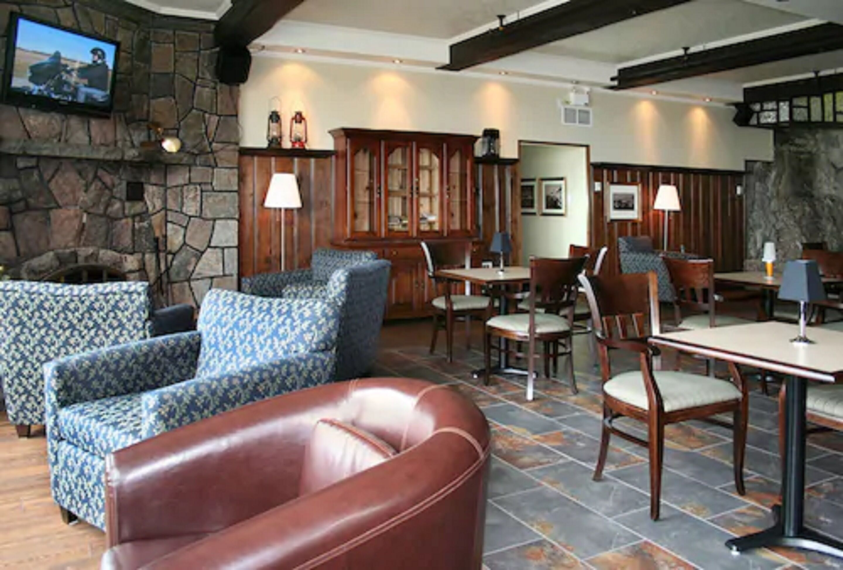 A cozy lobby with patterned sofas, a leather armchair, and a stone fireplace.