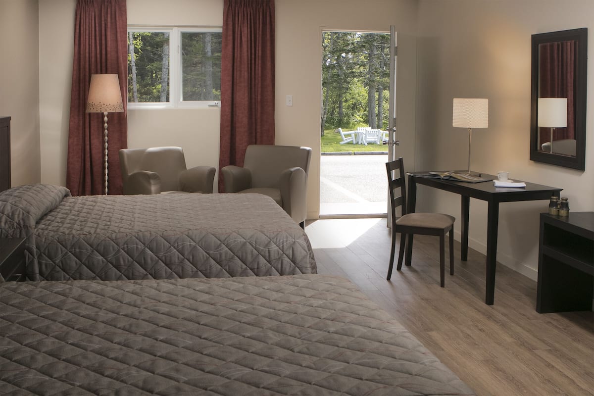 Ein Hotelzimmer mit zwei Betten, einem Schreibtisch, einem Stuhl und Blick ins Freie.