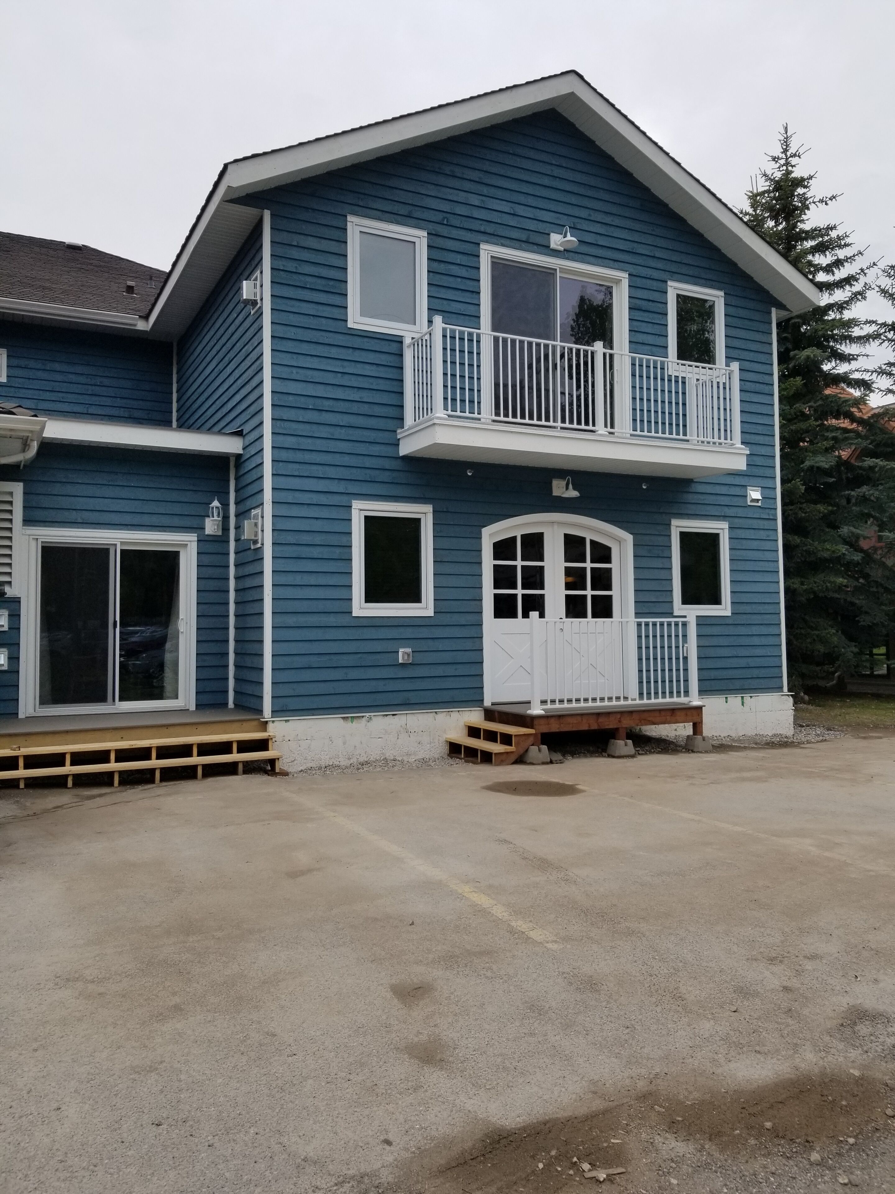 A two-story house with a balcony, a front door with glass panels, and a small porch area.