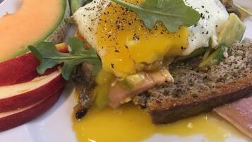 Un plato de desayuno con huevos pochados, jamón y verduras.