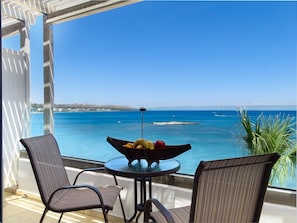 A balcony with a table and chairs, overlooking a coastal view with a clear sky. - Lido Star Beach (Rhodes)