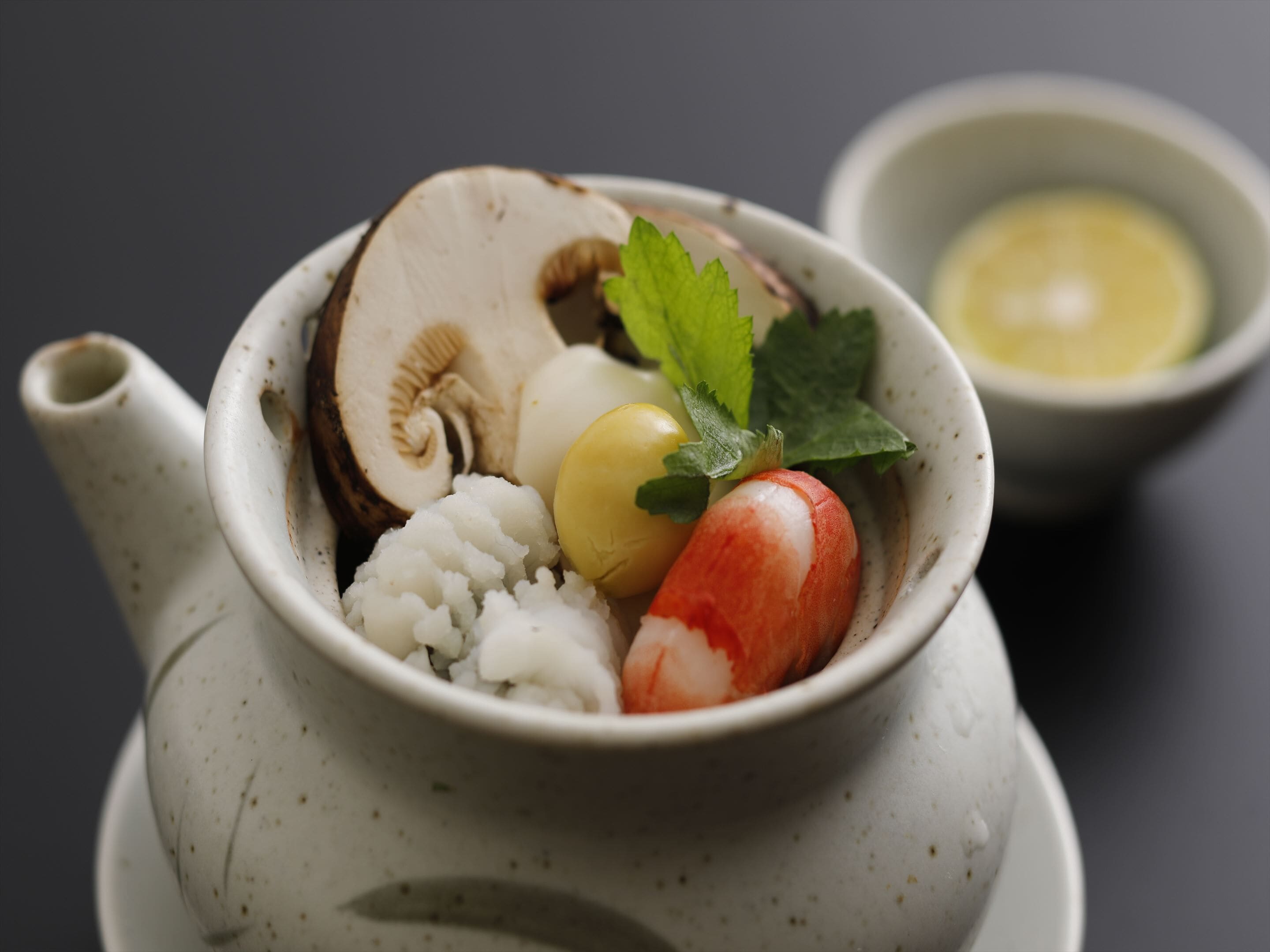 A teapot with a cup of tea, a small bowl of butter, and a radish.
