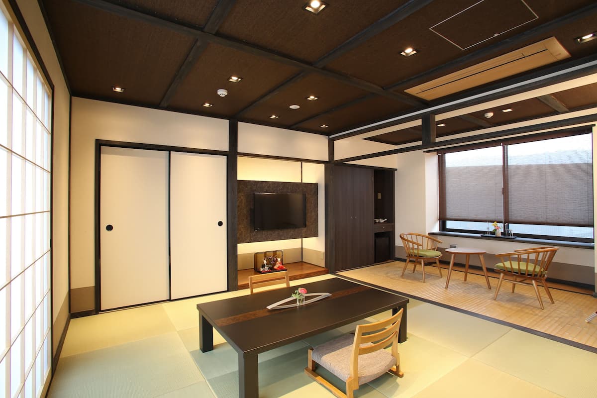 A traditional Japanese-style room with tatami flooring, a low table, and wooden chairs.