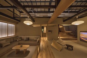 Un intérieur japonais traditionnel avec un sol recouvert de tatamis, un escalier bas en bois et un canapé fait de tatamis.