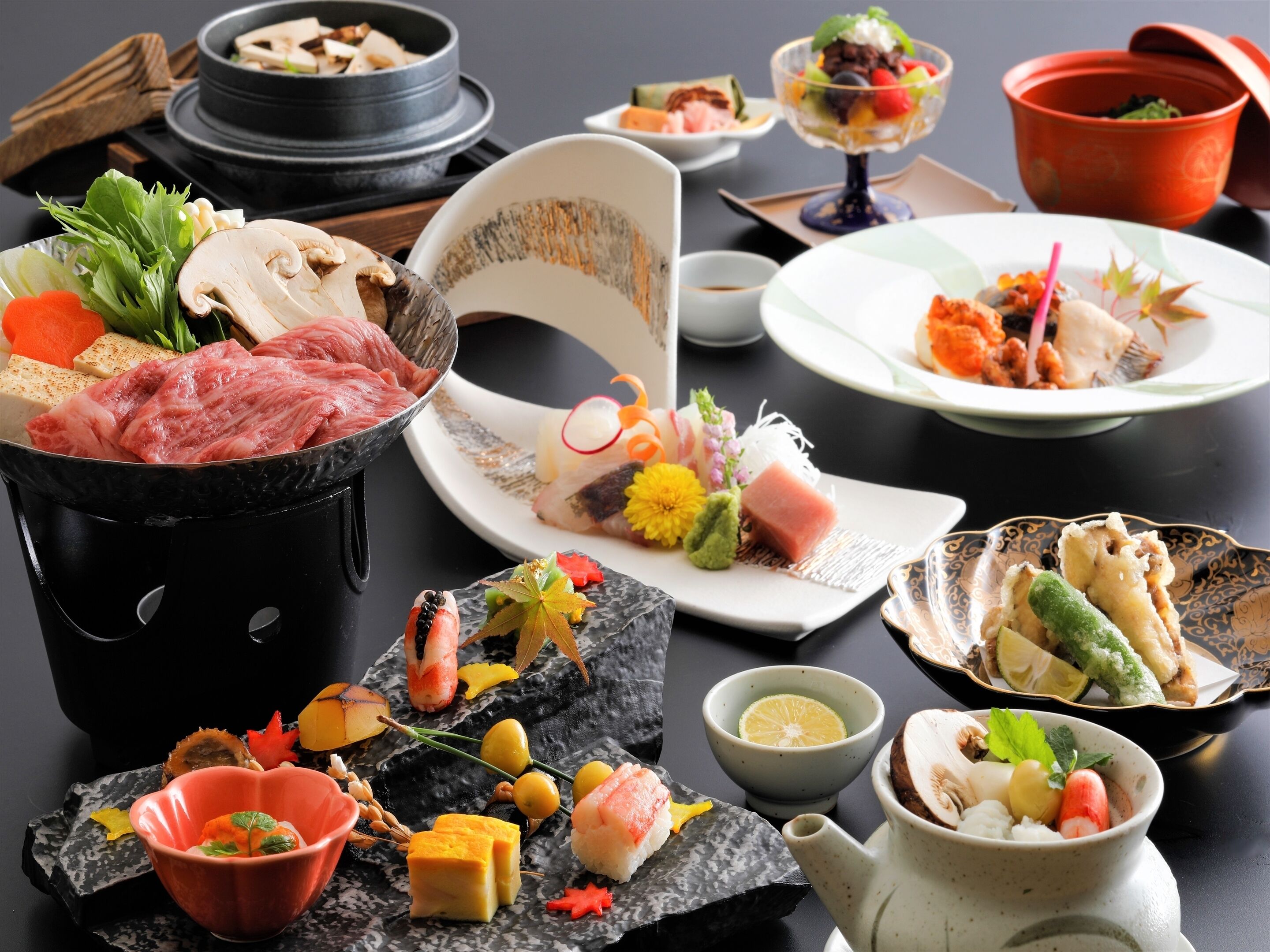 Variedad de platos japoneses, como sushi, sashimi y tempura, dispuestos sobre una mesa.