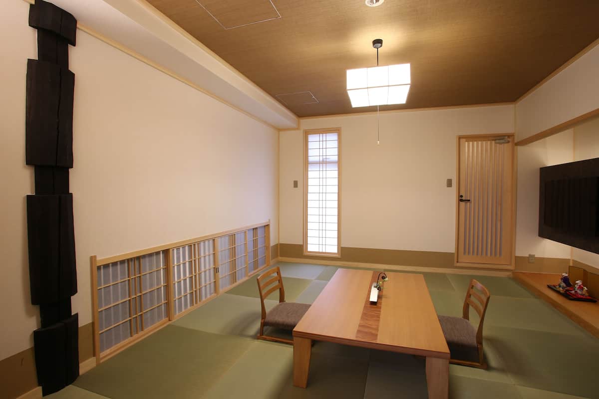 A traditional Japanese room with tatami flooring, a wooden table, and a sliding door.
