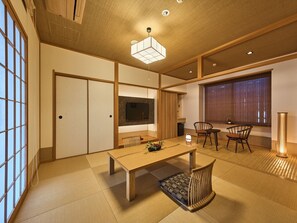 A traditional Japanese-style room with tatami flooring, a low table, and a TV mounted on the wall. - Wakasa Bettei (Nara)