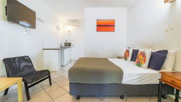 A hotel room with a bed, a desk, a chair, a TV, and a painting on the wall.