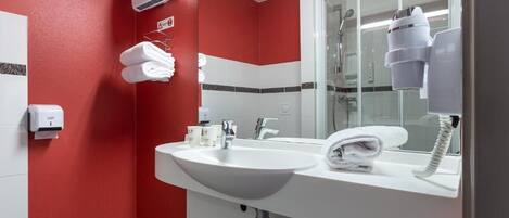 Une salle de bain avec un lavabo blanc, un miroir, un porte-serviettes et un sèche-cheveux.