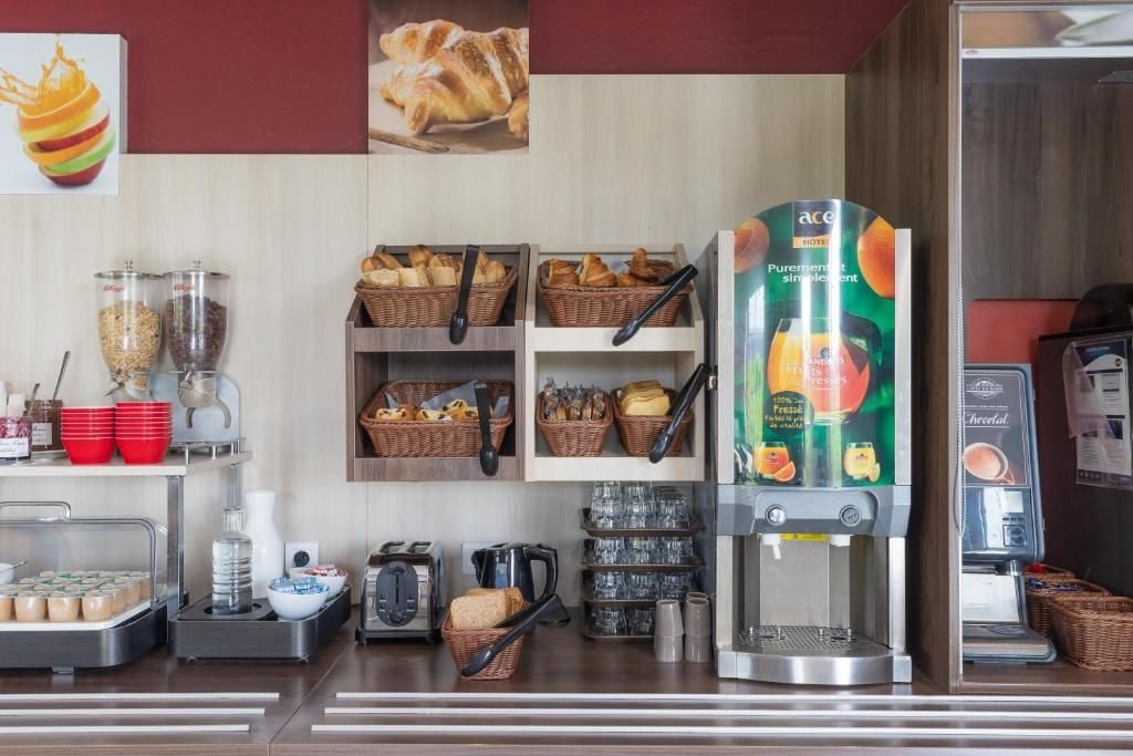 A hotel breakfast area with a coffee machine, bread baskets, and a juice dispenser.