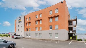 A modern hotel with a flat facade, multiple windows, and a parking lot in front. - ACE Hotel Arras-Beaurains (Beaurains)
