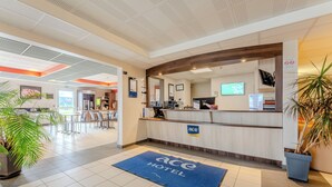 A hotel reception area with a blue mat, a reception desk, and a large mirror. - ACE Hotel Arras-Beaurains (Beaurains)
