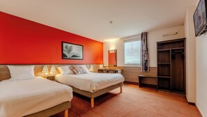 A hotel room with two beds, a red accent wall, a wooden floor, a wardrobe, and a TV. - ACE Hotel Arras-Beaurains (Beaurains)