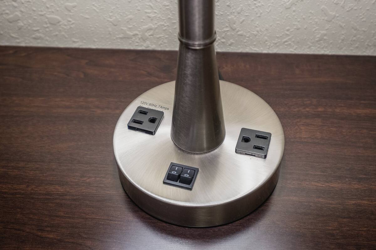 A metallic, round table with a central column, featuring two USB ports and two switches on its surface.