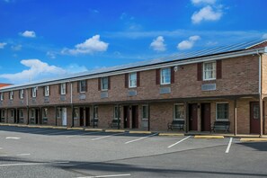 A row of single-story brick motel rooms with individual entrances and a parking lot in front. - Red Roof Inn Hershey (Hershey)