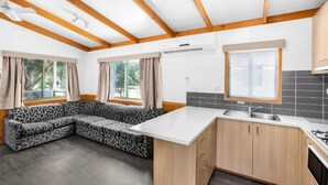 A modern kitchen with wooden beams, a built-in bench, and a large window. - Discovery Parks - Halls Gap (Halls Gap)