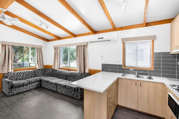 Une cuisine moderne avec des poutres en bois, un banc intégré et une grande fenêtre.