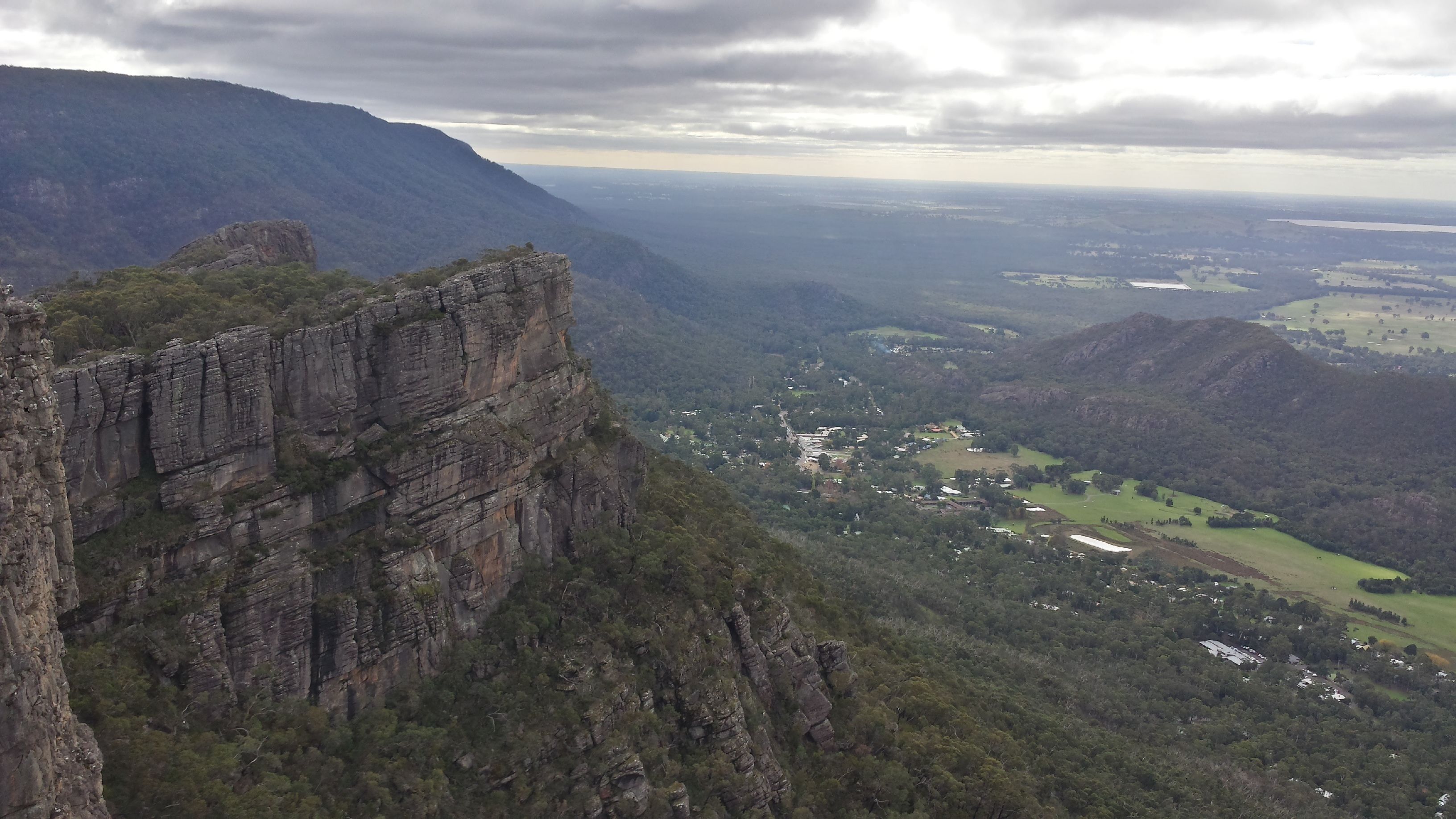 A mountainous landscape with a prominent rocky cliff and a valley below.