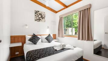 Ein Hotelzimmer mit Bett, einem Vorhangfenster, einem Deckenventilator und einem Wandbild.