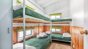 Ein Schlafzimmer mit Etagenbetten, Holzwandverkleidung, einem Fenster und einer Tür.