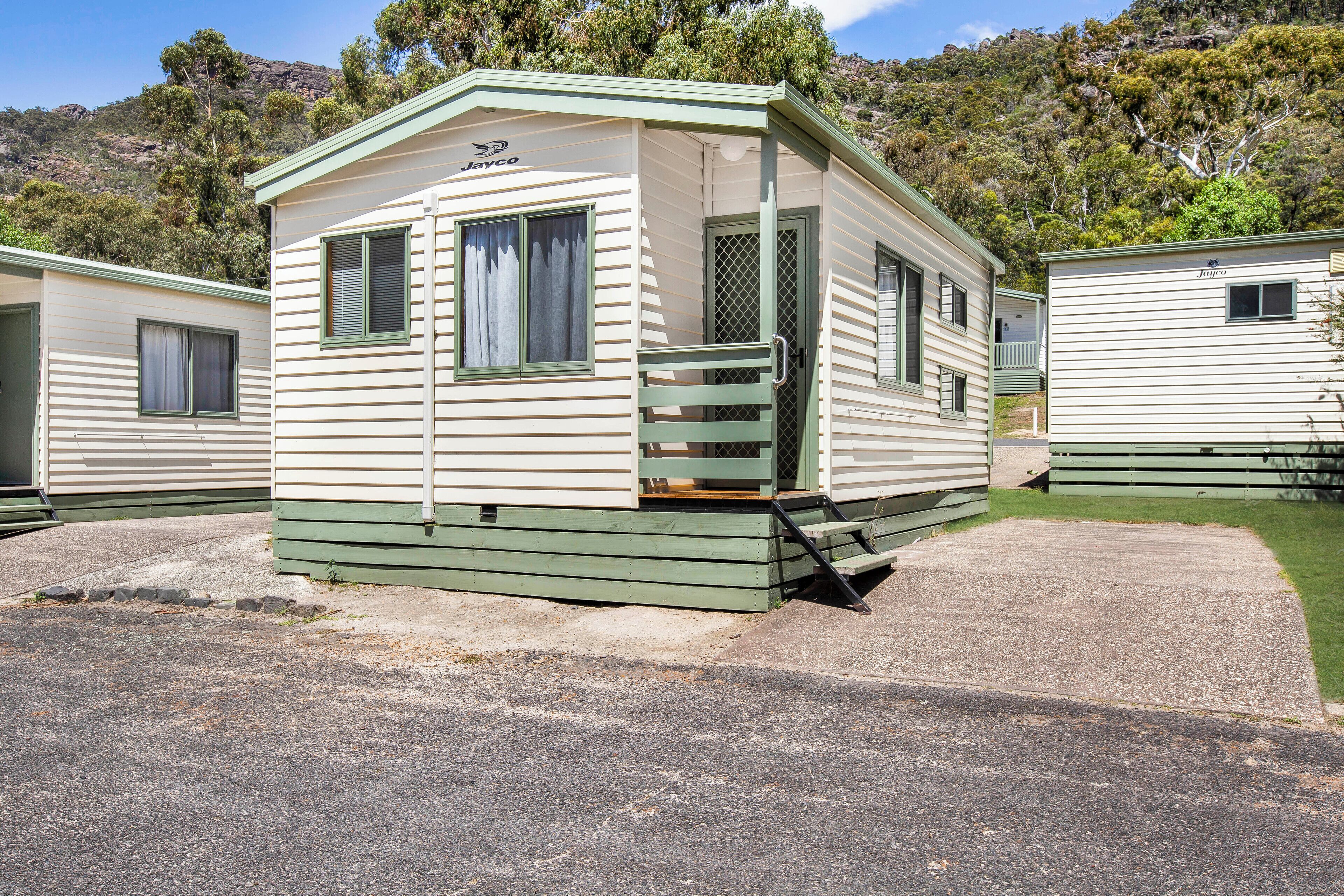 Une maison mobile de plain-pied, dotée d’une véranda et d’un petit escalier menant à l’entrée.