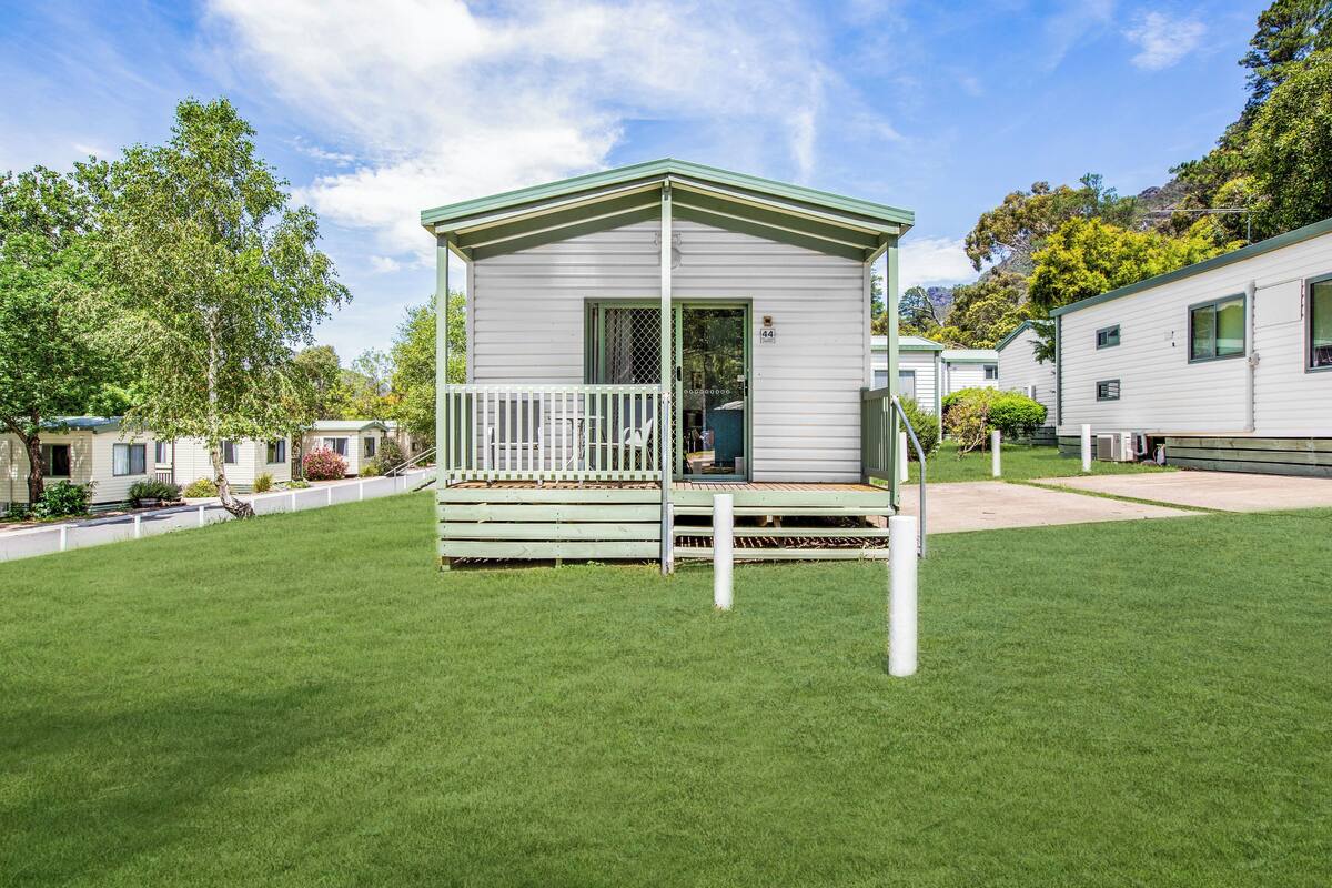 Een kleine, gelijkvloerse stacaravan met een veranda en een omheinde tuin.