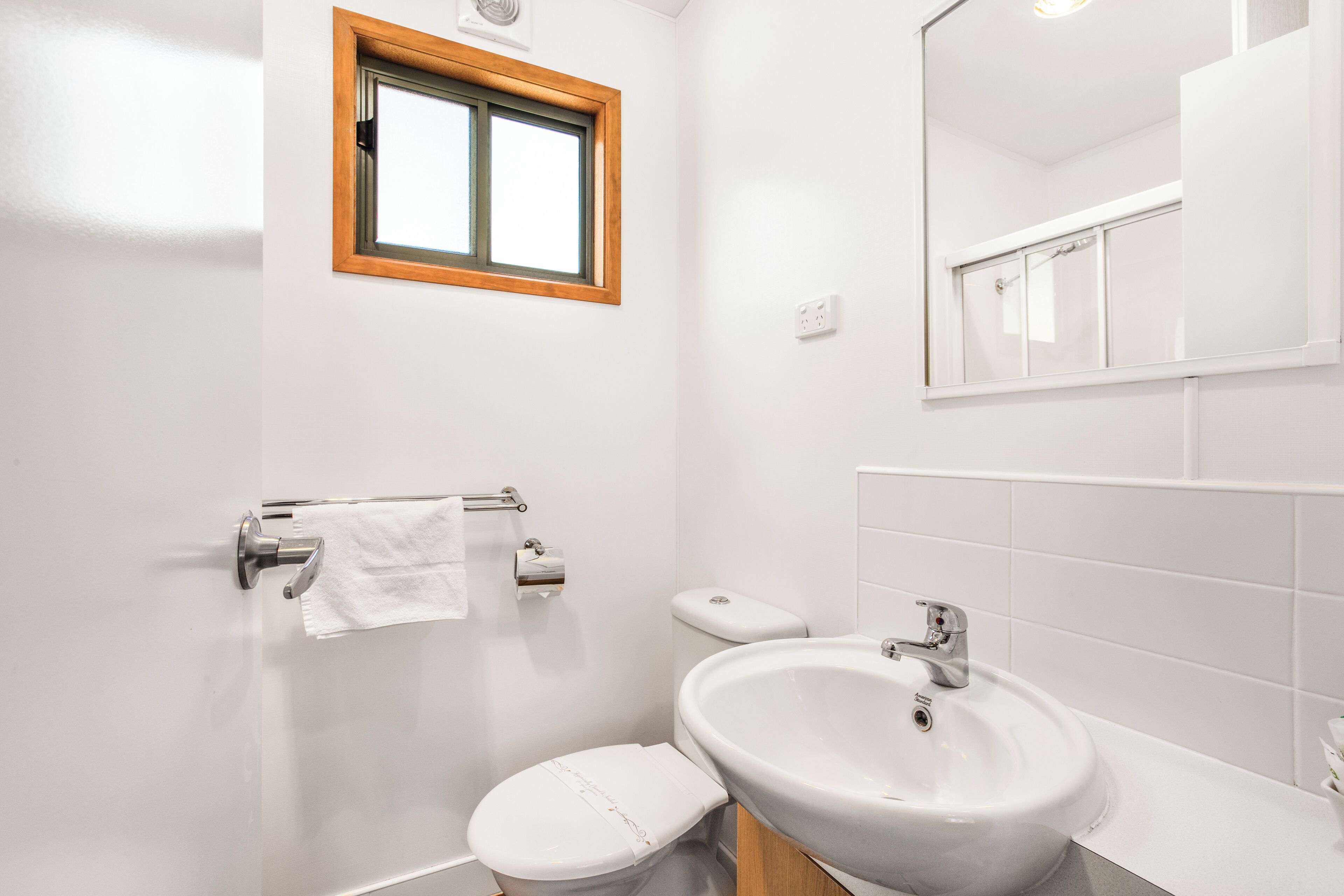 A bathroom with a toilet, sink, and window.