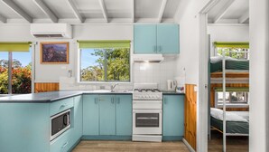 A compact kitchen with teal cabinets, a stove, and a microwave. - Discovery Parks - Halls Gap (Halls Gap)