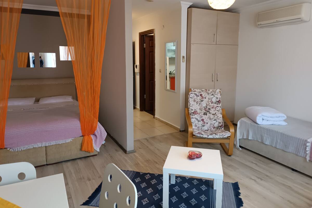 Ein Hotelzimmer mit Bett, Sessel, Nachttisch, Kleiderschrank und Klimaanlage.