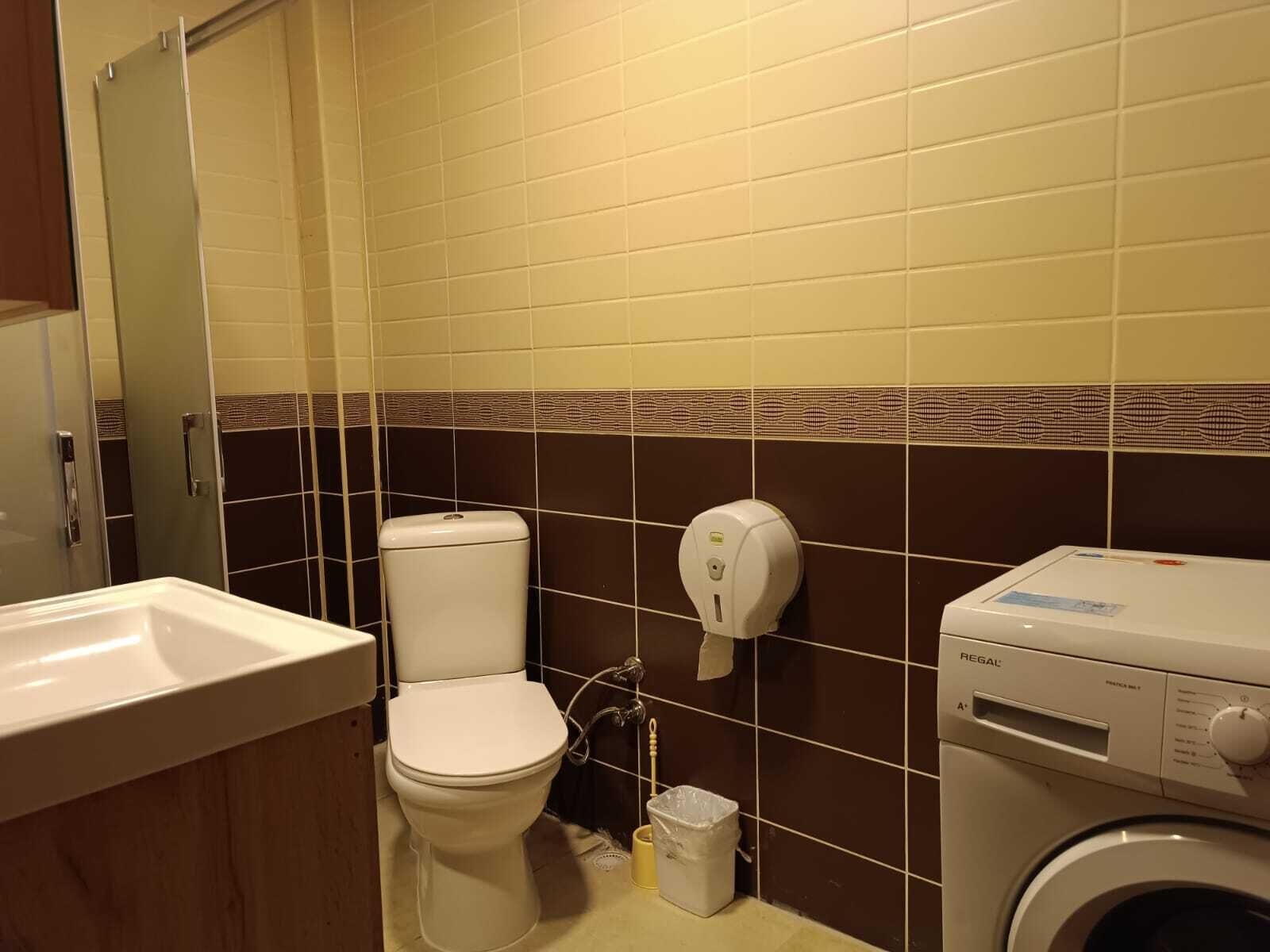 Un baño con inodoro, lavamanos y lavadora.
