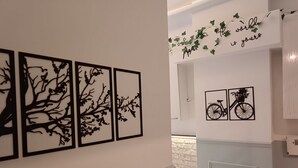 A hallway with four black framed wall art depicting tree branches, a wall-mounted sign with ivy and the phrase "the world is yours," and a small bicycle illustration. - The City Residence (Çanakkale)