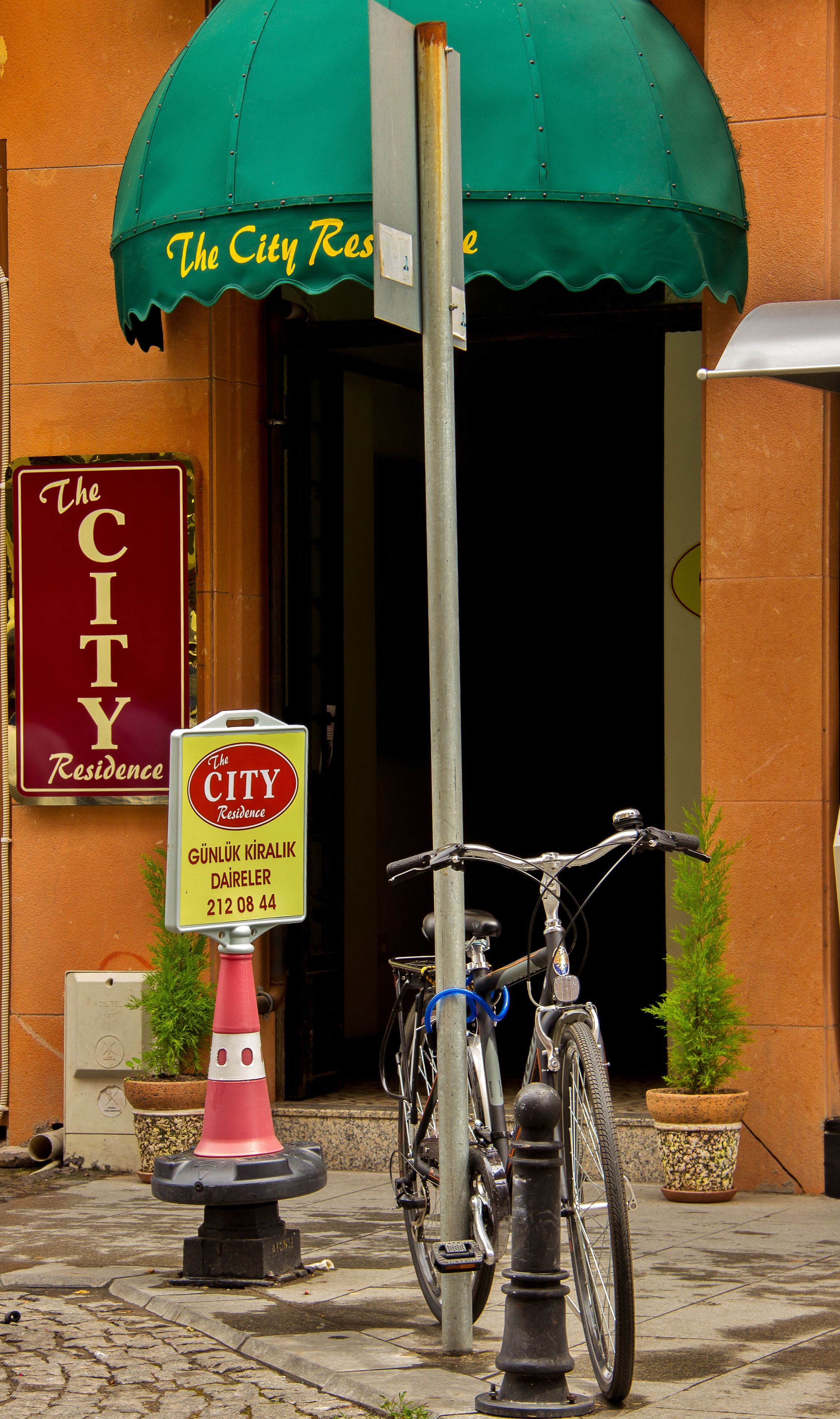 Entrada de un edificio con toldo verde que dice 'The City Residence'.
