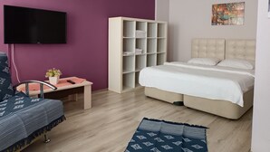 A modern bedroom with a large bed, a TV, a wardrobe, and a painting on the wall. - The City Residence (Çanakkale)