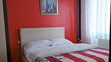 A bed with a white headboard, a red and white striped blanket, and a framed picture on the wall.