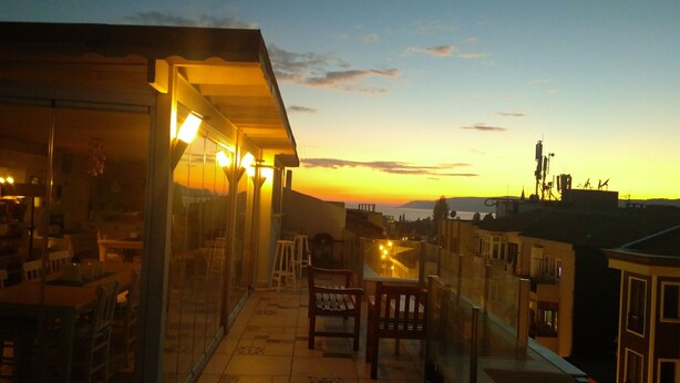 A balcony with a view of the sunset, tiled flooring, and a few chairs. - The City Residence (Çanakkale)